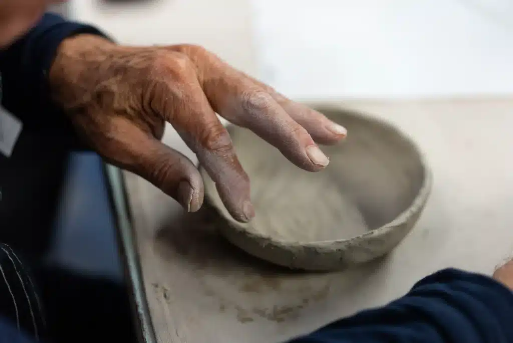 A hand touching a clay bowl during a handbuilding workshop at Murai Pottery